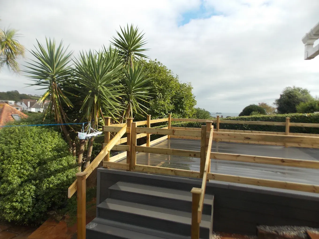 Grey composite deck with a timber balustrade and steps down to the lawn